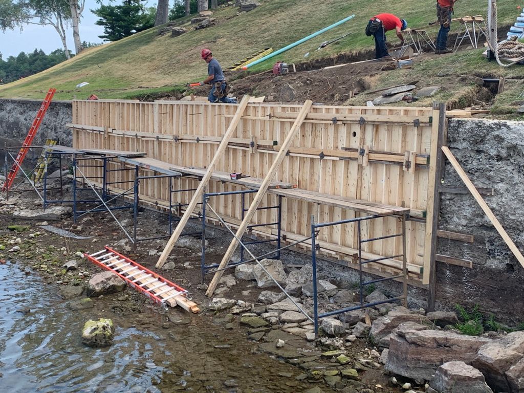 A worker inspecting the concrete foundation of a residential home.