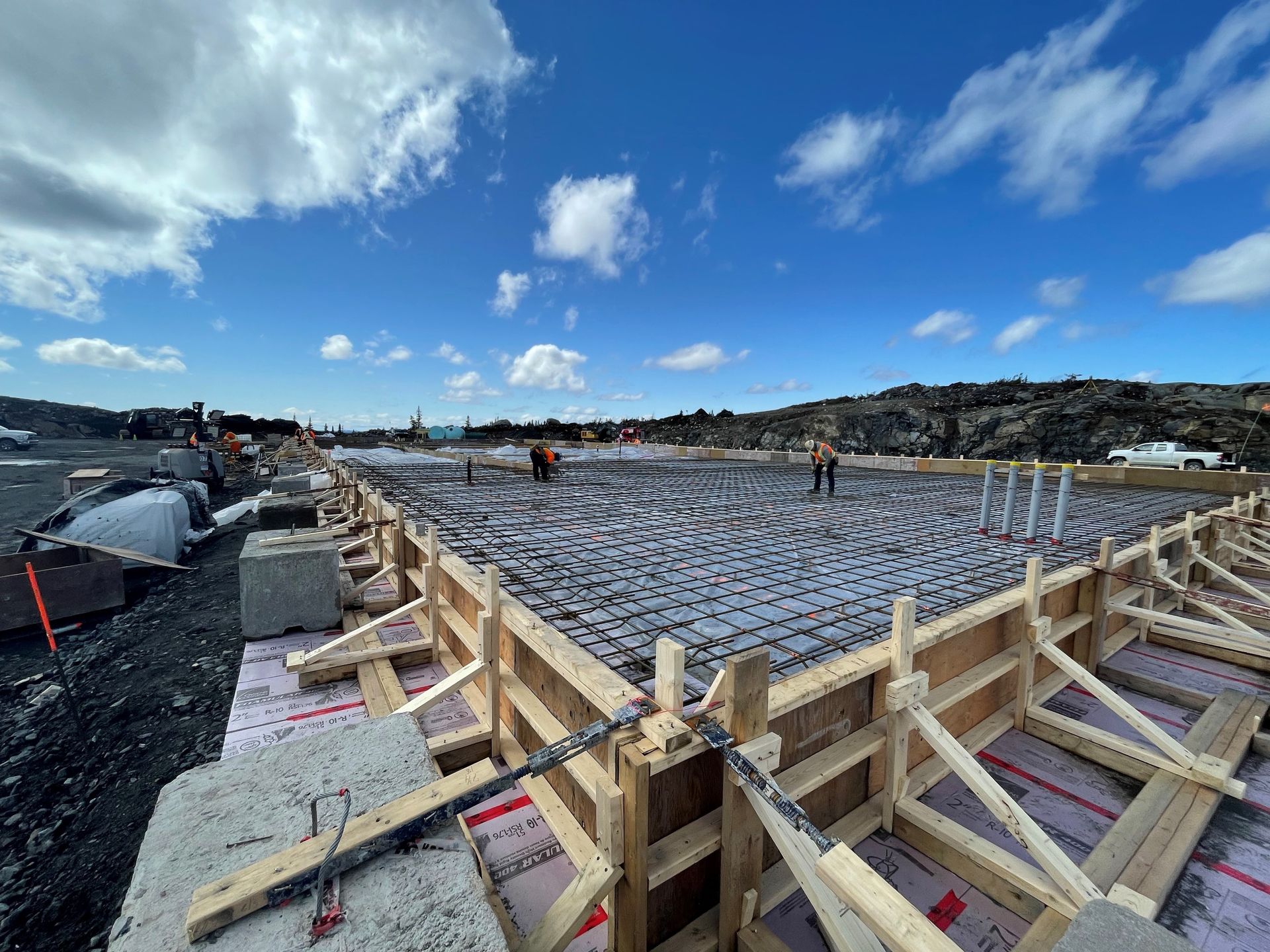 A worker pouring and finishing a fresh concrete slab on a civil engineering site.